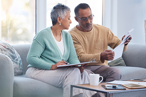 a couple on their couch reviewing their end of year checklist for finances.