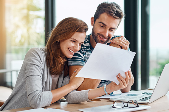 a man and woman looking at a strategic finance plan on paper and smiling