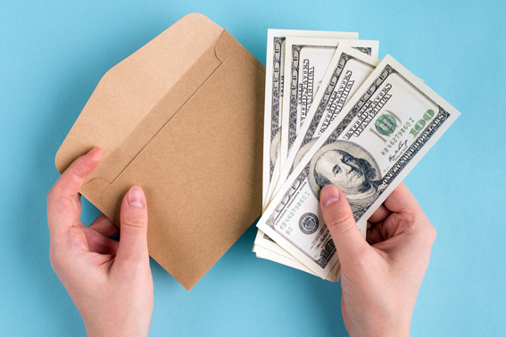 hands handling cash and an envelop for the cash stuffing money hack.