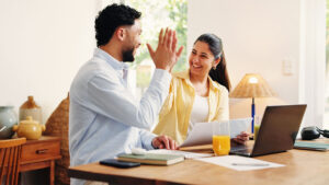 Man and woman high-fiving at table doing work for a blog about how to pay off credit card debt fast