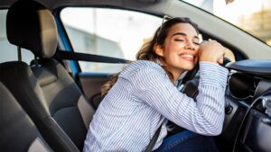 Woman hugging steering wheel for a blog about best auto loan rates in delaware